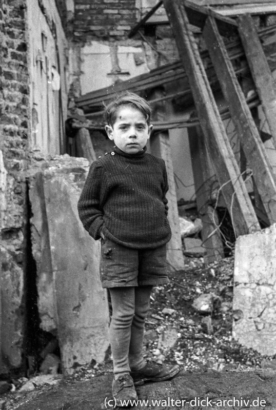 Junge vor zerstörtem Haus 1946