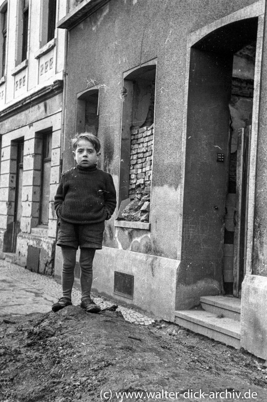 Junge vor zerstörtem Haus 1946